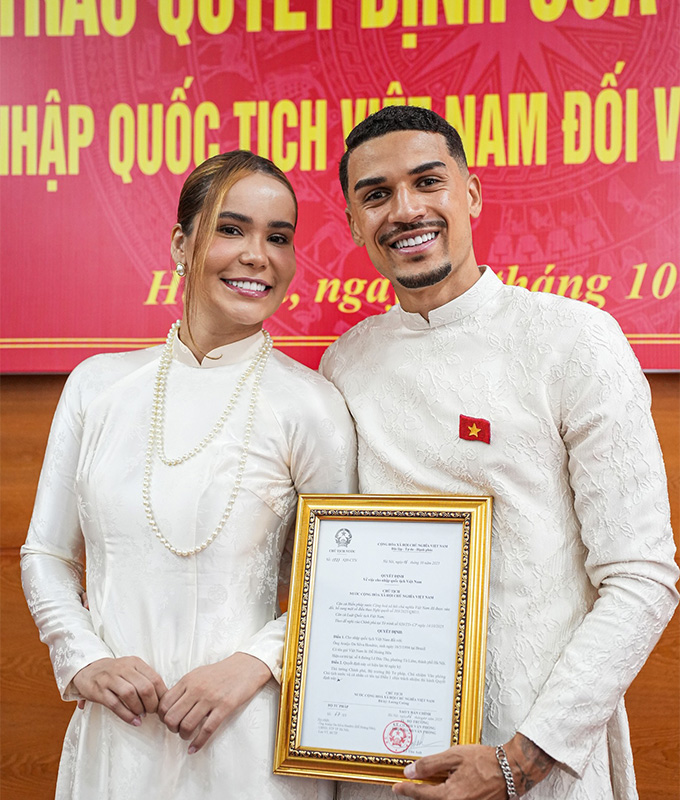 Đỗ Hoàng Hên và vợ mặc áo dài truyền thống có cờ đỏ sao vàng khi nhận quốc tịch Việt Nam