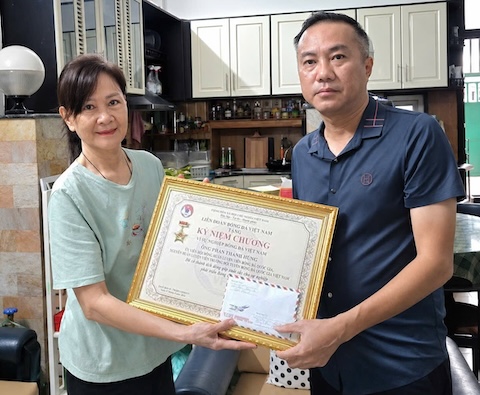 Bà xã HLV Phan Thanh Hùng nhận kỷ niệm chương do Phó chủ tịch VFF Nguyễn Xuân Vũ trao tặng. Ảnh: VFF